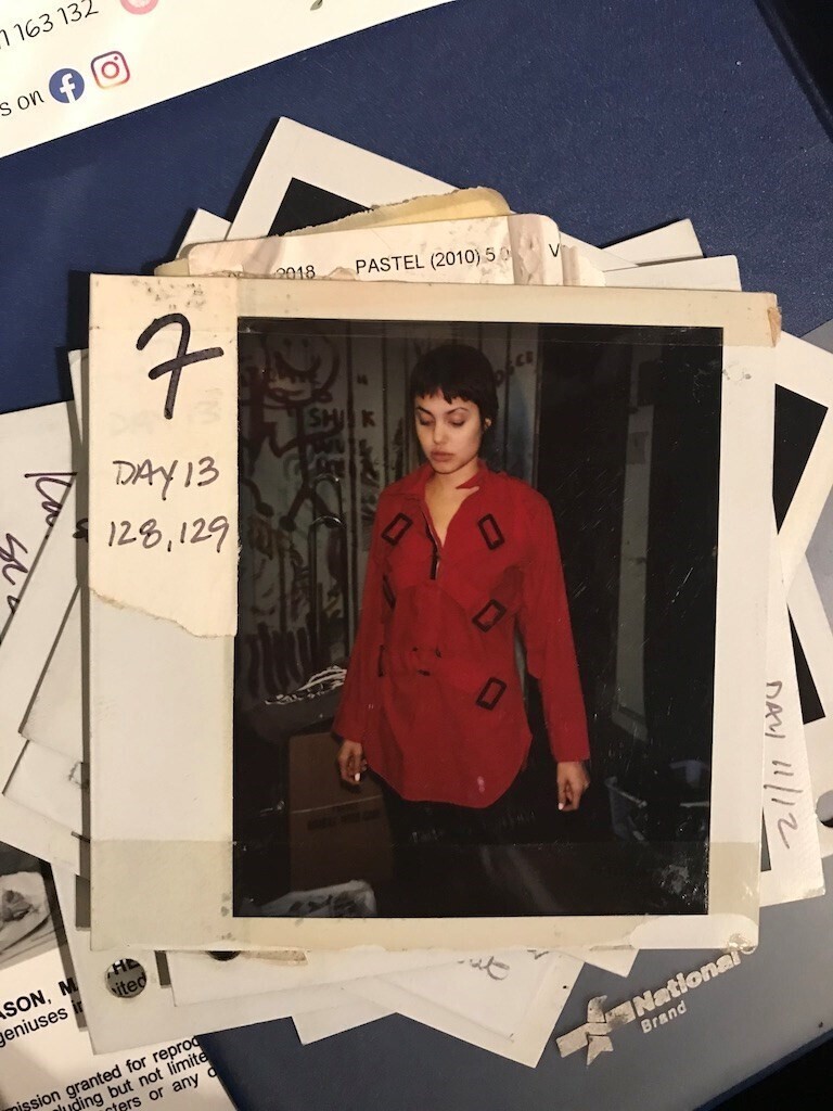 A polaroid photo of Angelina Jolie in a red and black outfit.