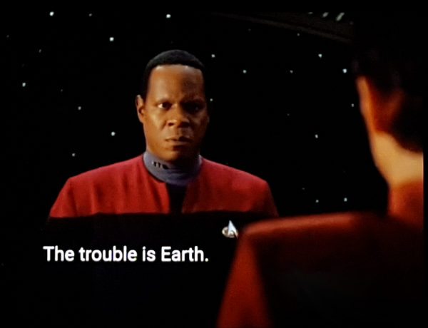 DS9 scene. We're in the Sisko's ready room. The back wall is a window to dark space spotted with distant stars. We see the Sisko standing and looking back at Major Kira. Screenshot pov is looking over her shoulder. Closed caption reads, "The trouble is Earth."