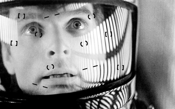 Dave, from 2001: A Space Odyssey, staring out from inside his space helmet, with a look of overwhelm on his face. A collection of brackets, parenthesis, and em dashes is superimposed over the helmet's face shield.