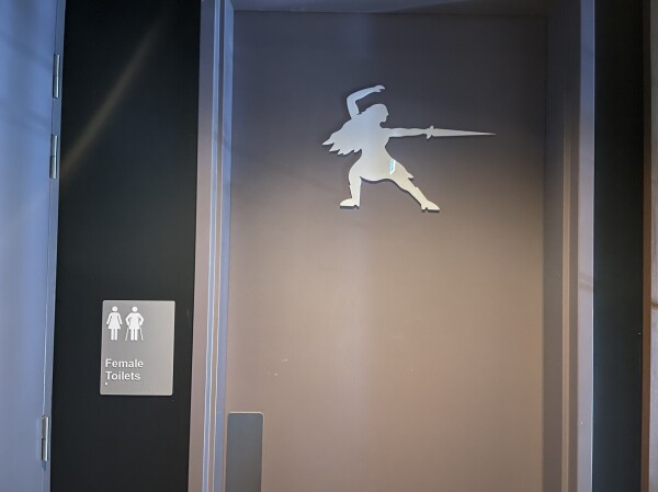 The door to a women’s bathroom with a silhouette of a person brandishing a sword, with long hair and a skirt